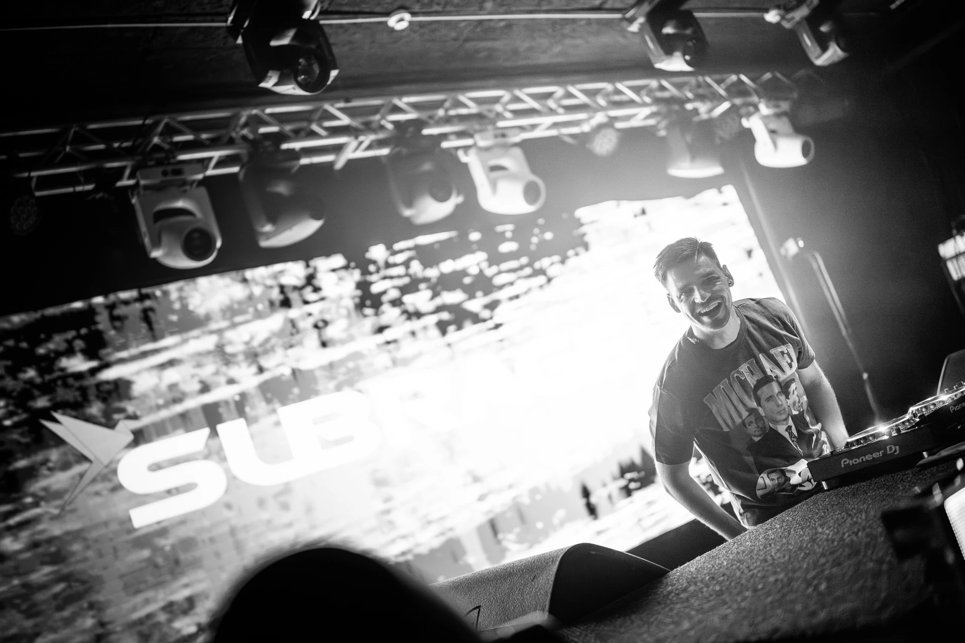 Subrage smiling behind the DJ booth during a live set